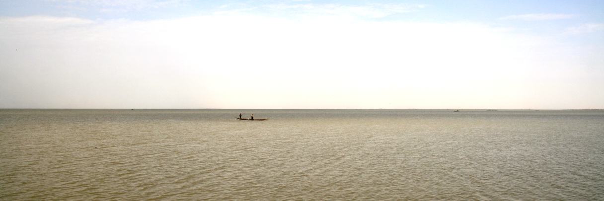 Petite embarcation isolée sur une vaste étendue d'eau calme.